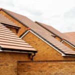 Exterior view of yellow brick row house with yellow roof tiles.