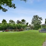 The backyard of the house with a large green lawn